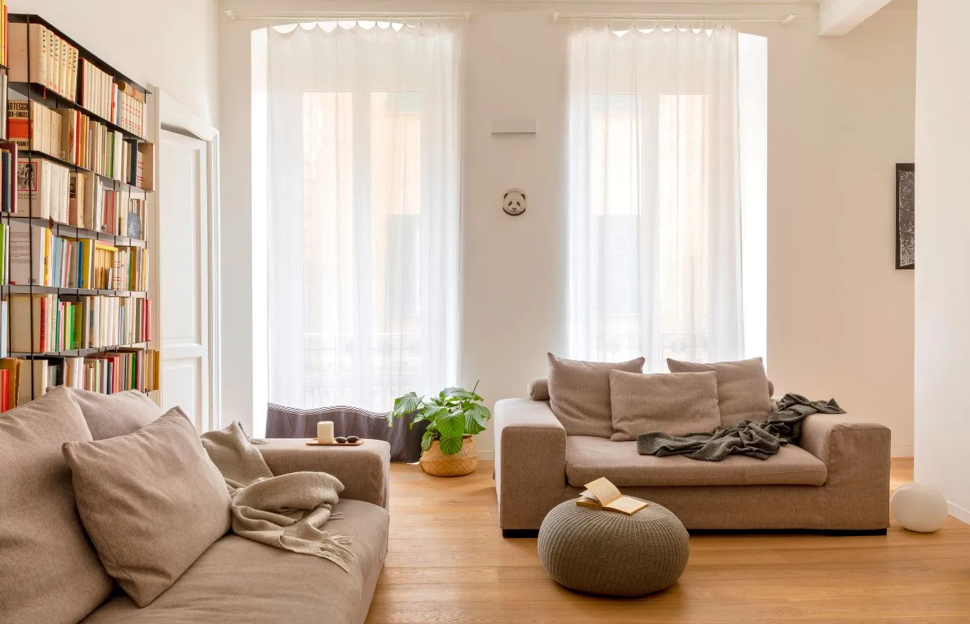 Salotto moderno e minimal, con poltrona e divano comodi, luce naturale e libreria