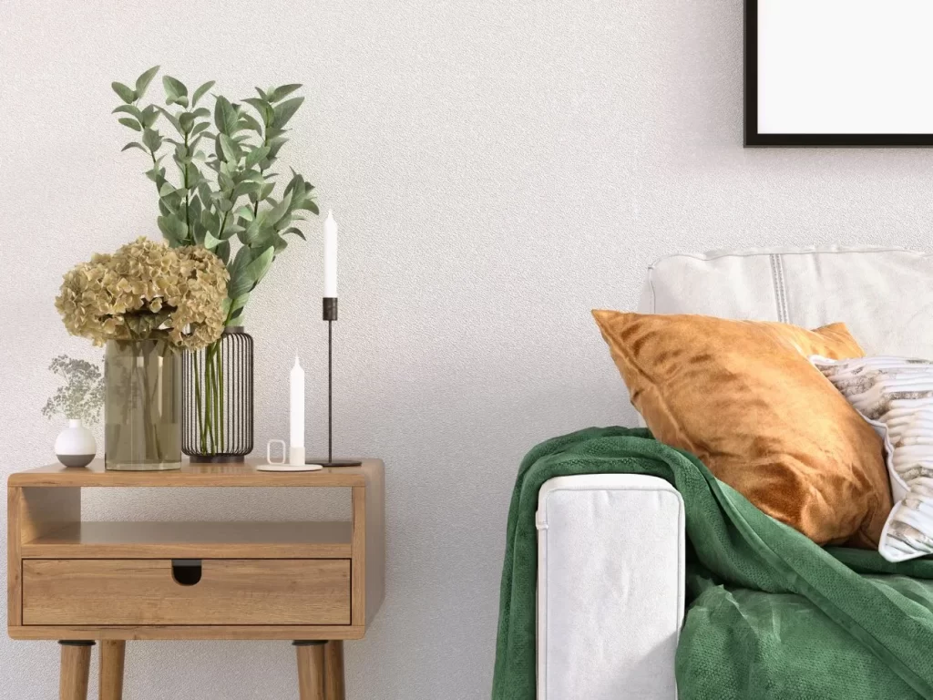 Immagine di divano bianco con accanto un tavolino in legno su cui si trovano due vasi di fiori e due candele