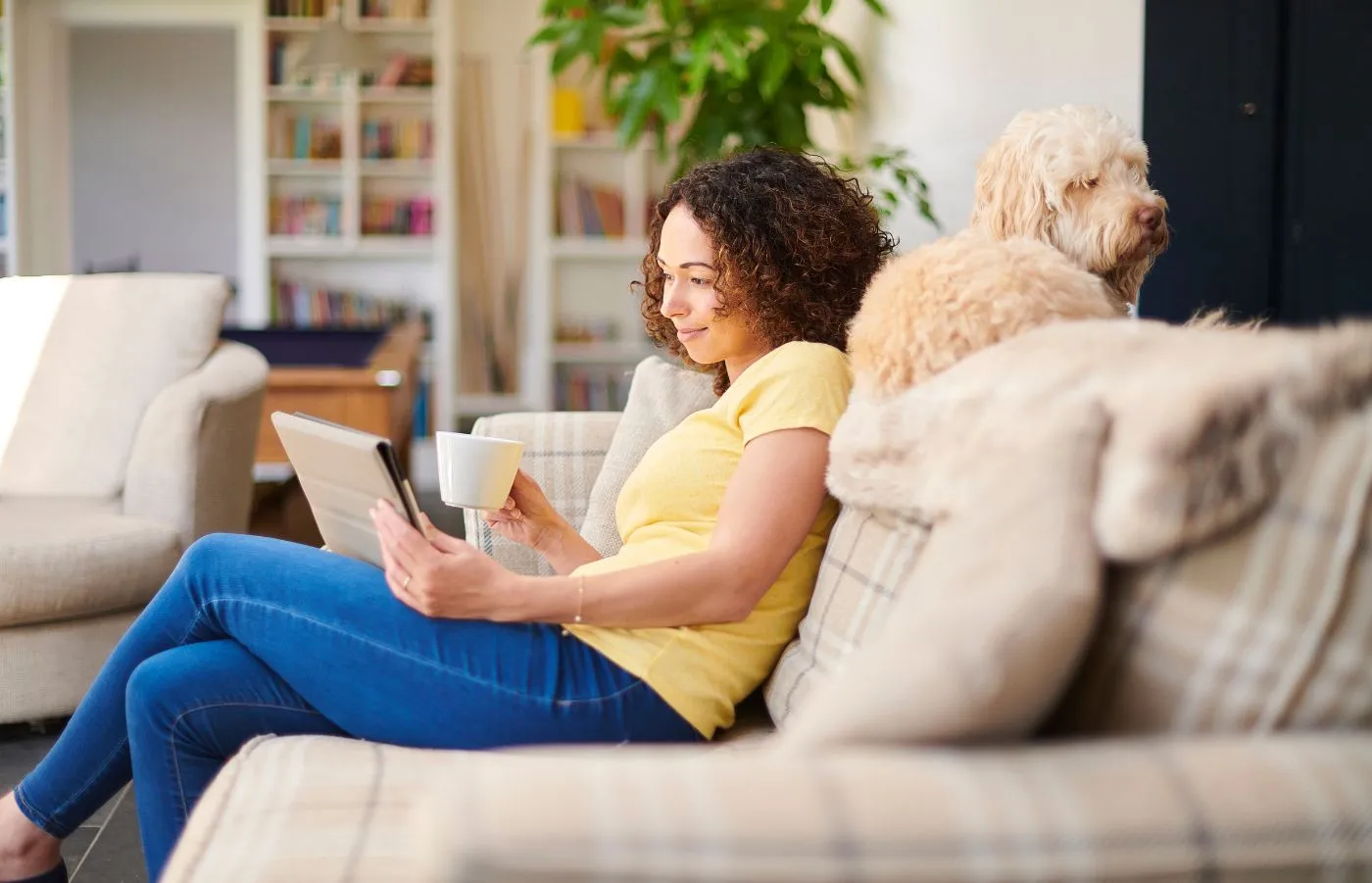 Donna su divano che legge notizie di settore su tablet
